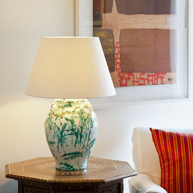 Glazed painted table lamp with cream shade on table with abstract picture