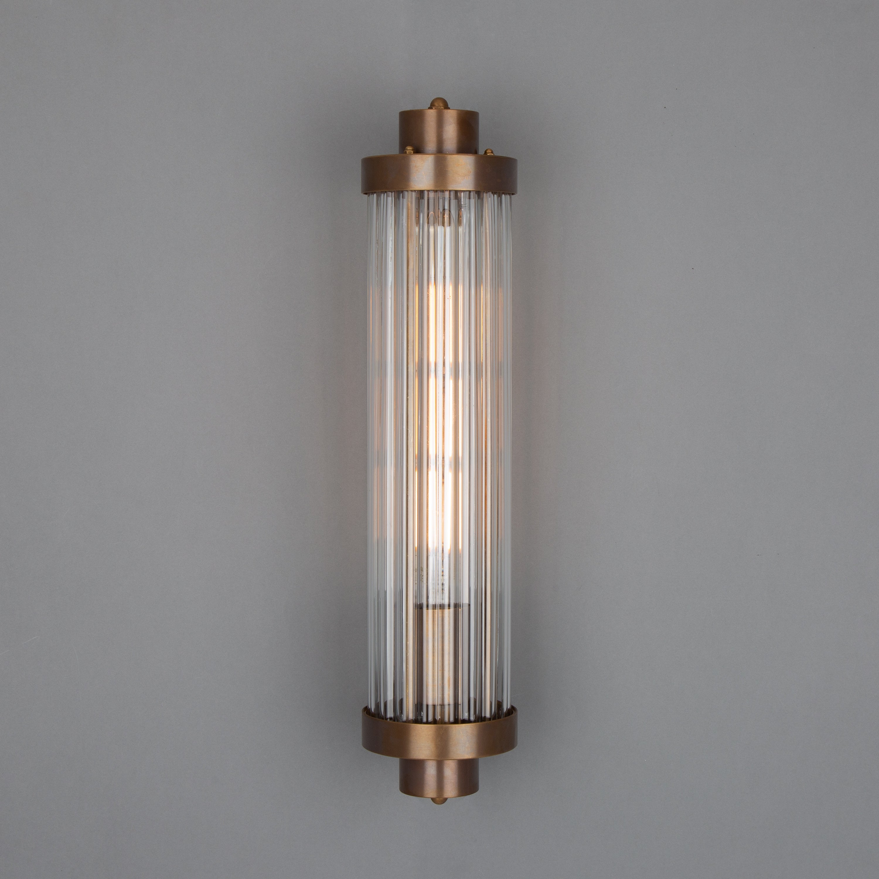 Retro Bathroom wall light fixture in Antique Brass on a grey background