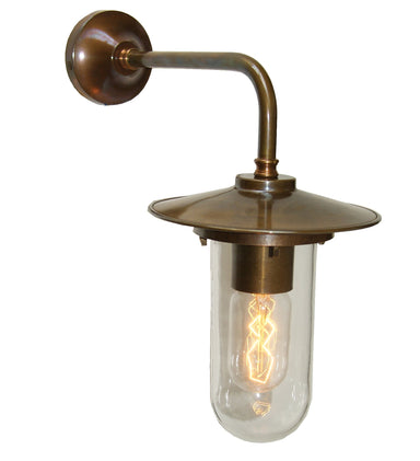 Vintage-style wall-mounted light fixture in antique brass with clear glass shade and exposed bulb on a white background