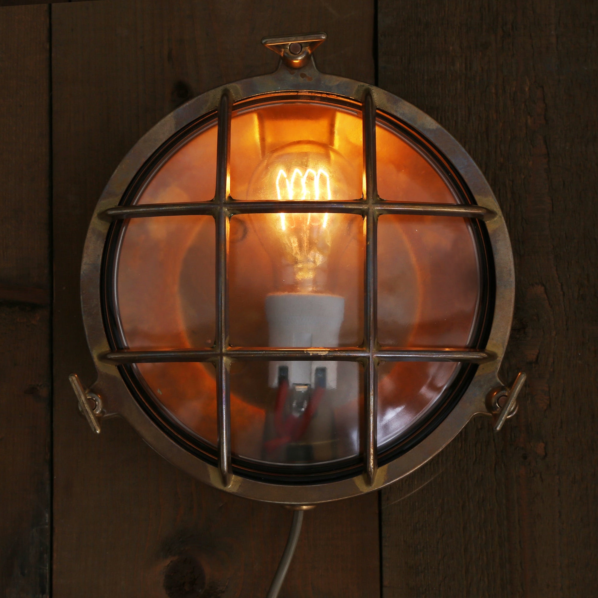 Round wall light fixture with a glowing bulb on a wooden background