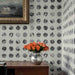 Room interior with polka dot wallpaper, wooden cabinet, and vase of flowers.
