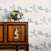 Wooden cabinet with decorative elements against a wallpapered wall with small figures.