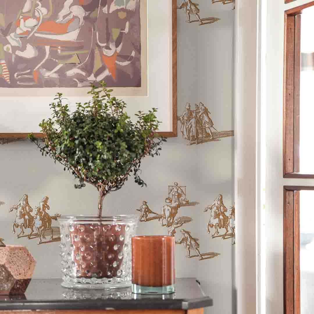 Decorative wall with gold wall art and a potted plant on a table.