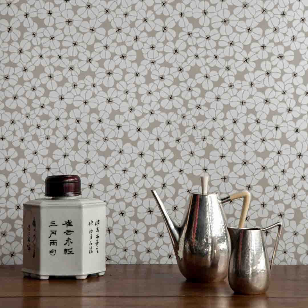Decorative teapots on a wooden surface with floral wallpaper in the background