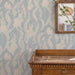 Wallpaper with rabbit and leaf pattern, wooden dresser below, mirror on wall.