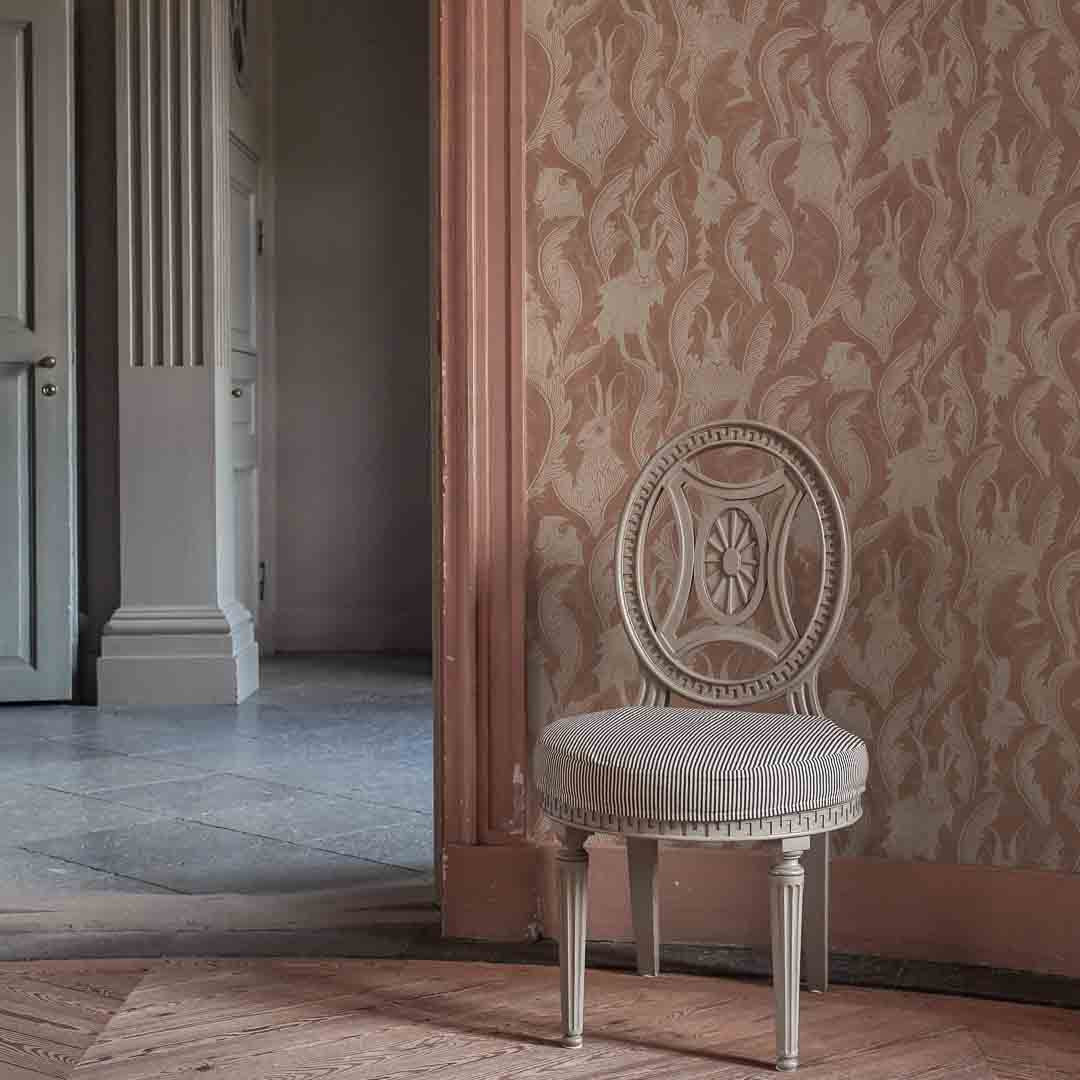 Vintage chair against a patterned wall in an elegant room.