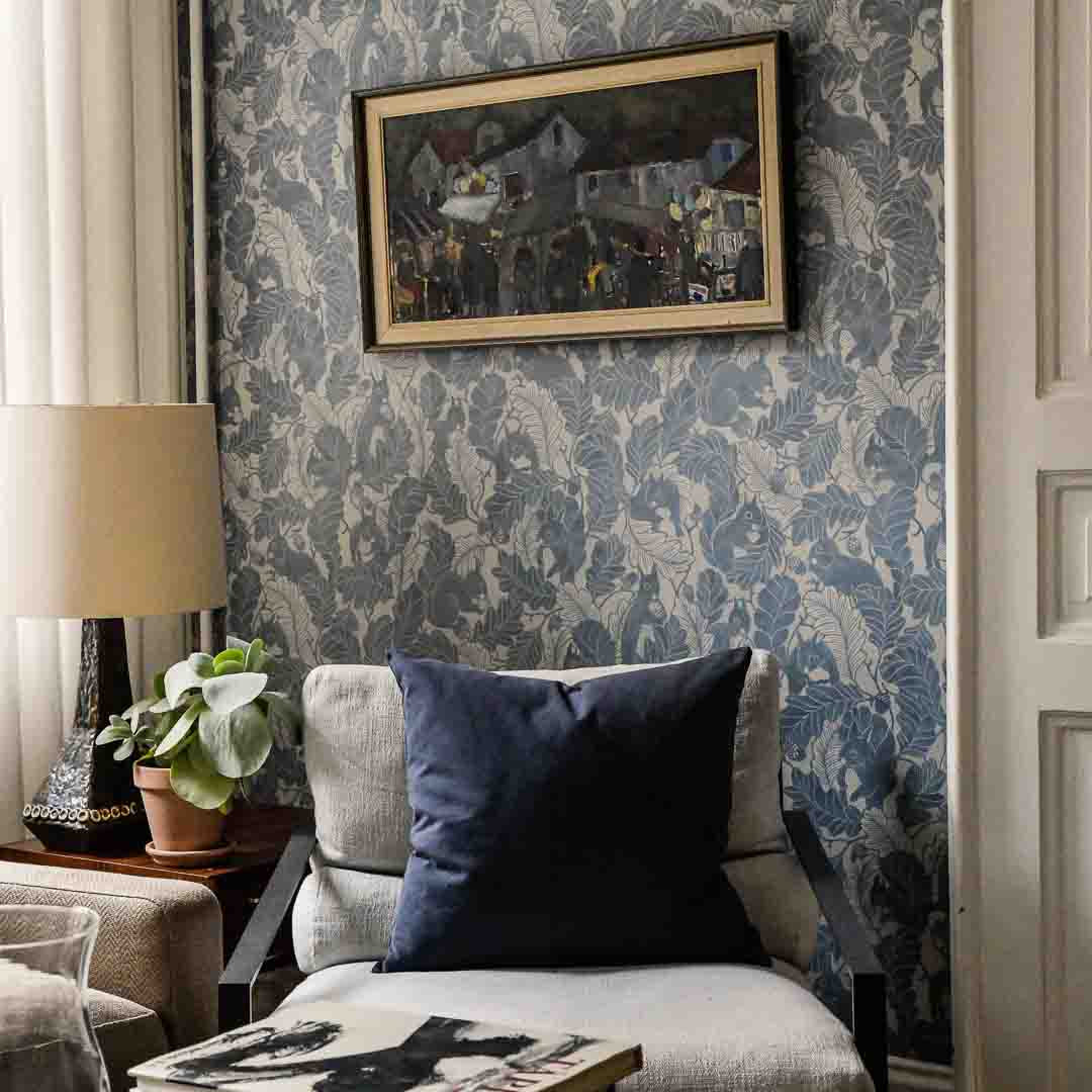 Living room with floral wallpaper, gray armchair, and framed artwork.