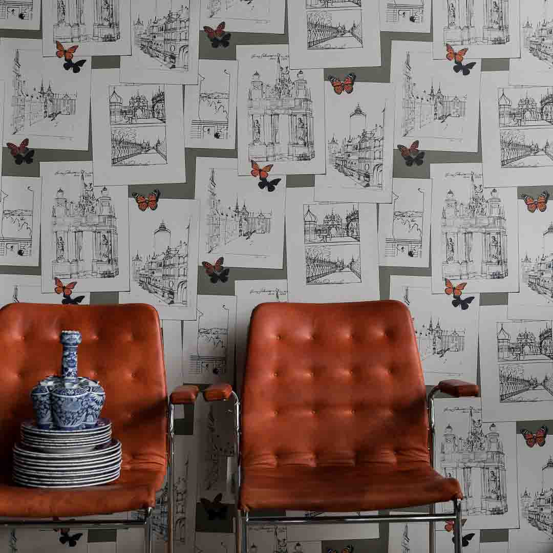 Two orange chairs in front of a wall with architectural drawings and butterfly illustrations.