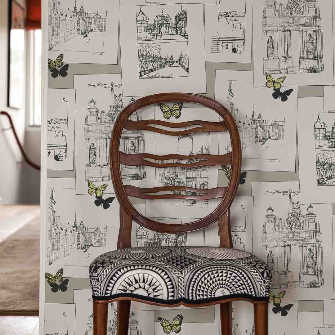 Wooden chair with patterned seat against a decorative wallpaper background