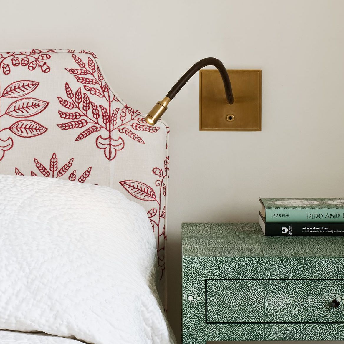 Brass and leather LED reading wall light beside bed and table with books
