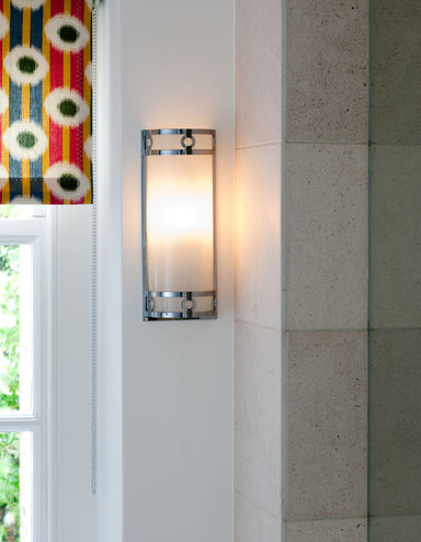Chrome and glass art deco style wall light beside window with colourful blind