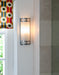 Chrome and glass art deco style wall light beside window with colourful blind