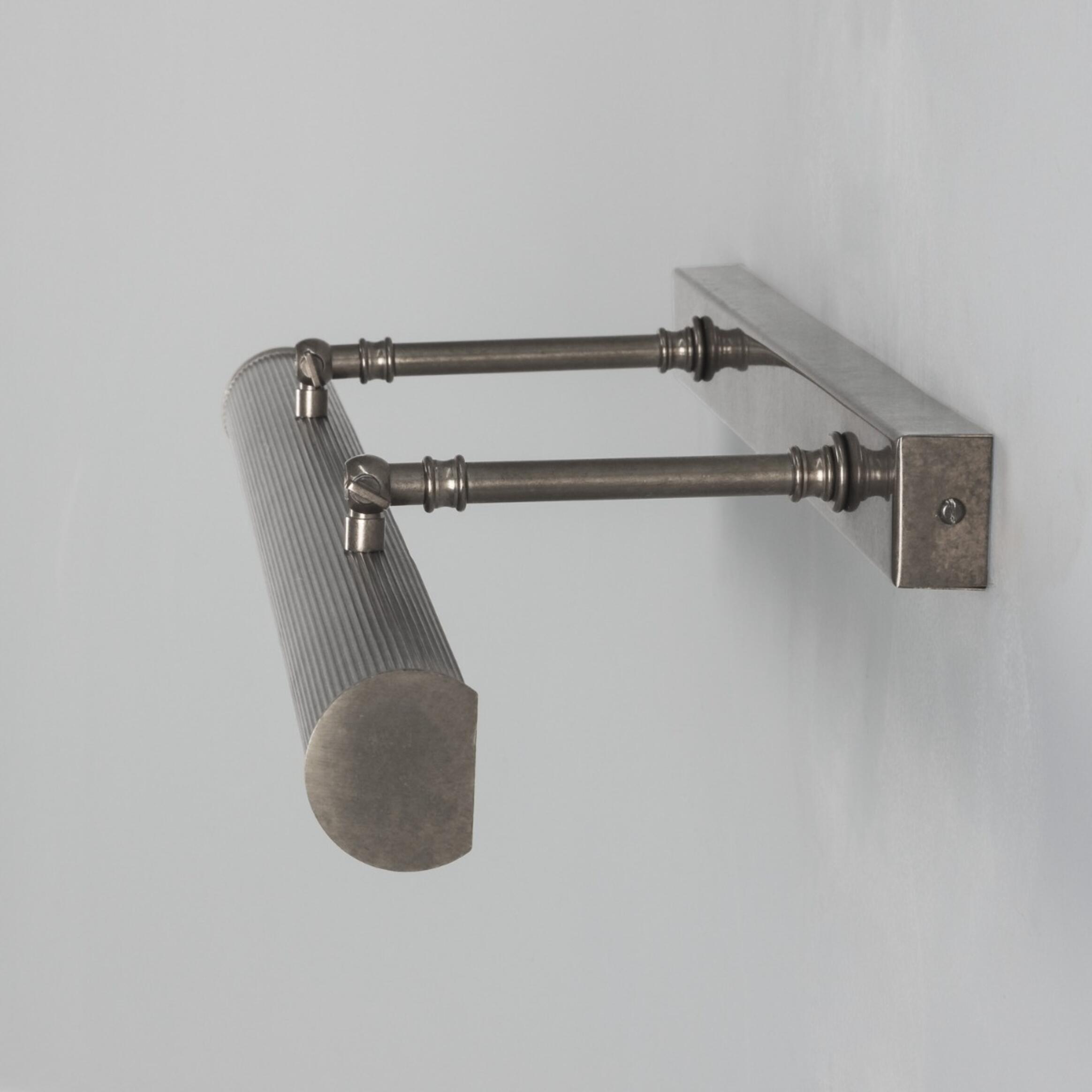 Metallic wall-mounted lamp with a cylindrical shade on a light gray background