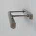 Metallic wall-mounted lamp with a cylindrical shade on a light gray background