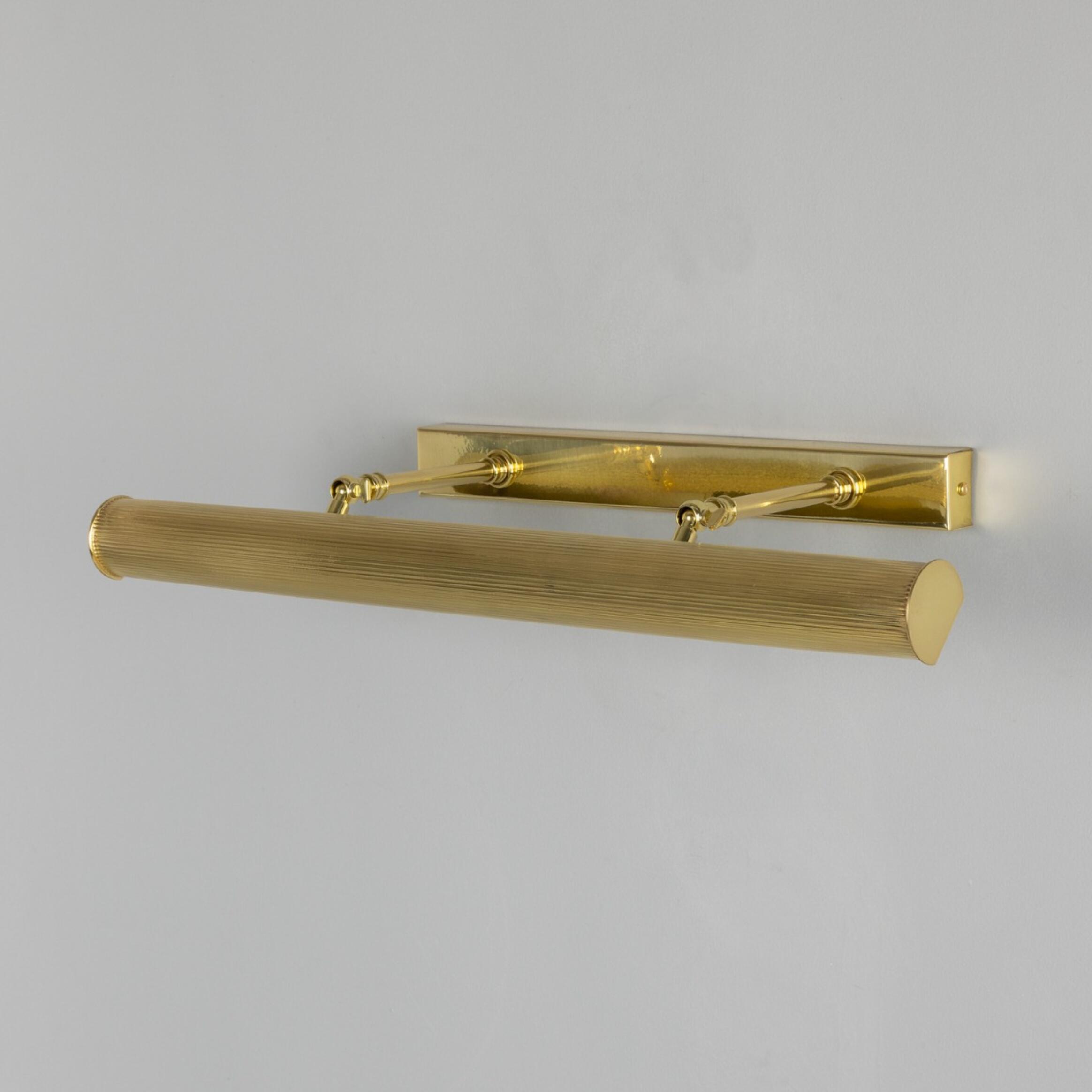 Brass wall-mounted light fixture on a grey background