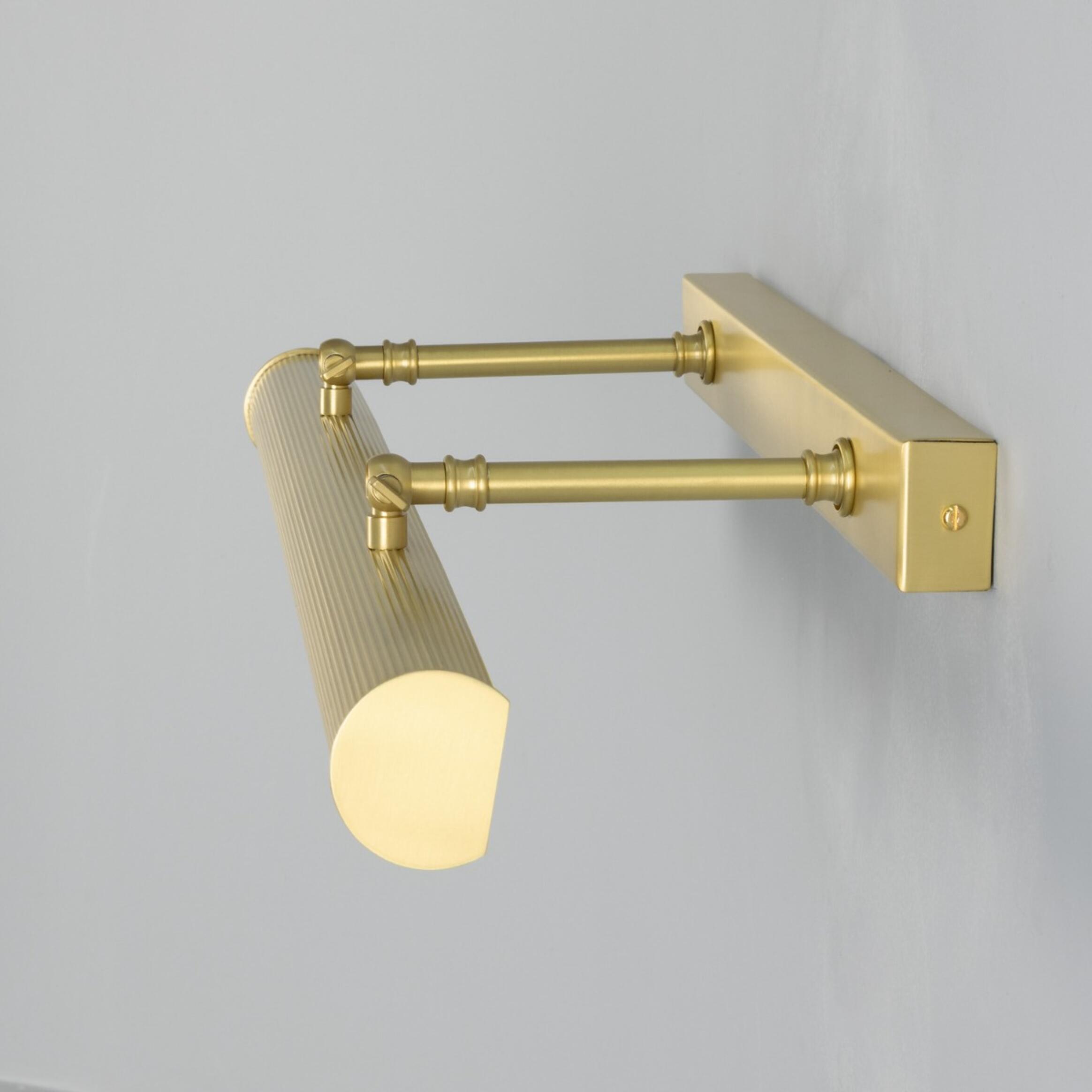 Brass wall-mounted light fixture on a grey background
