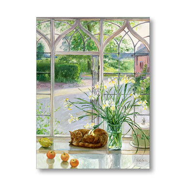 Cat resting on a windowsill with flowers and apples, looking out a large ornate window.