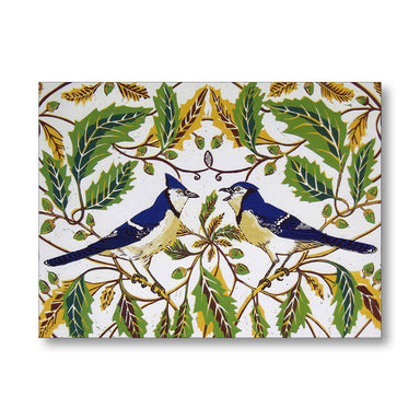 A square decorative art print or panel featuring two bluebirds perched among green and gold-toned leaves on a white background, shown against a light gray studio backdrop.